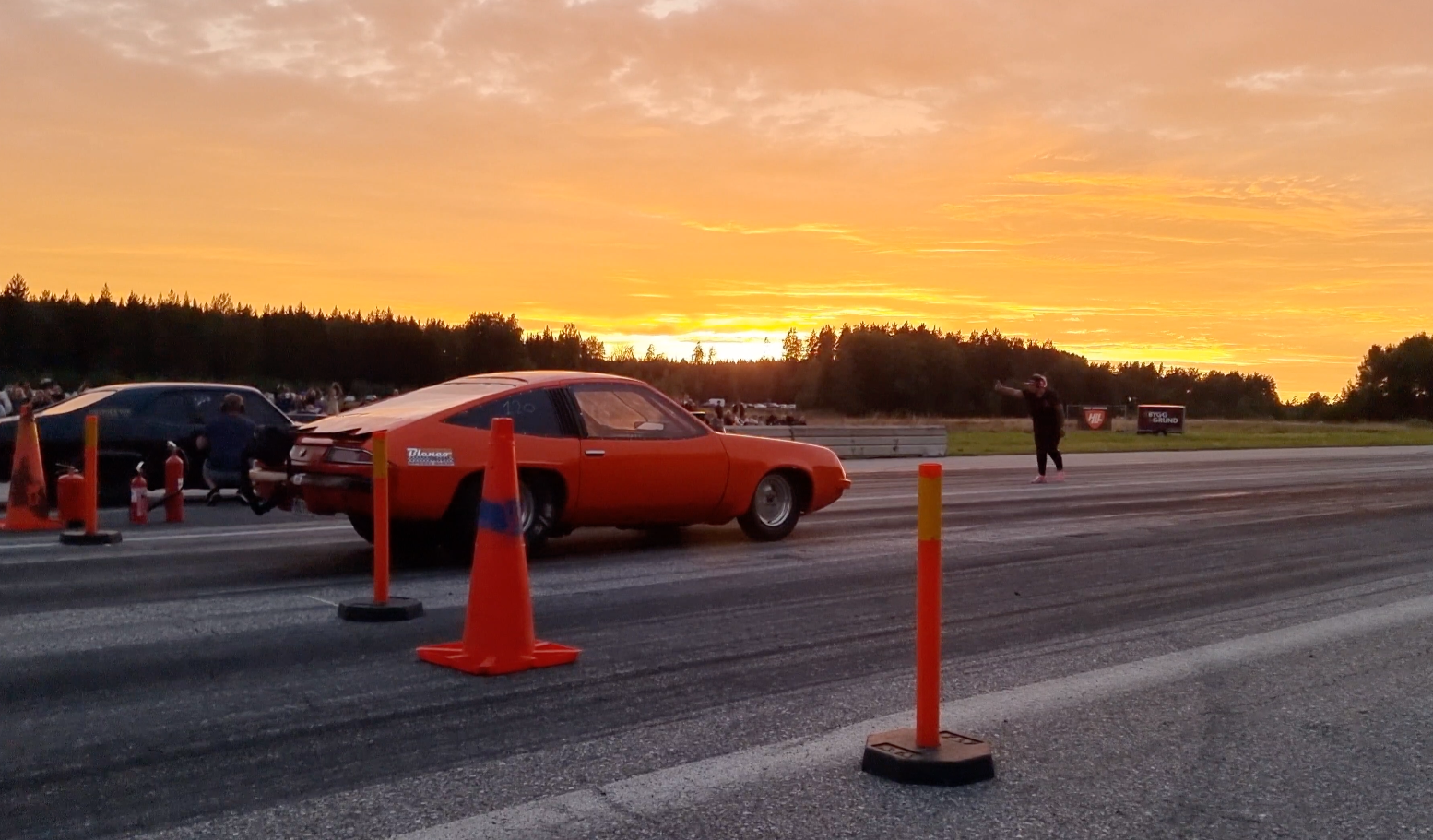 Orange car on a racetrack with sunset in the background